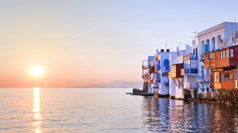 Mykonos town glows as the sun sets over the sea