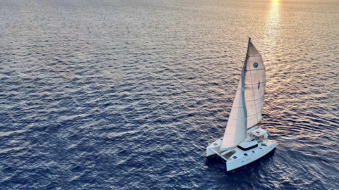 The catamaran sails gracefully into the sunset, offering a picturesque view