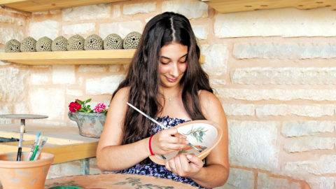 A young artisan carefully painting pottery, preserving the rich tradition of Cretan craftsmanship.